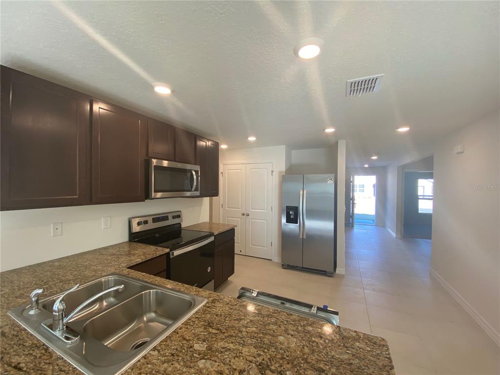 308 Hickory Course Radiel Ocala, FL 34472 - Photo 7 of 24 a kitchen with stainless steel appliances granite countertop a refrigerator and a stove