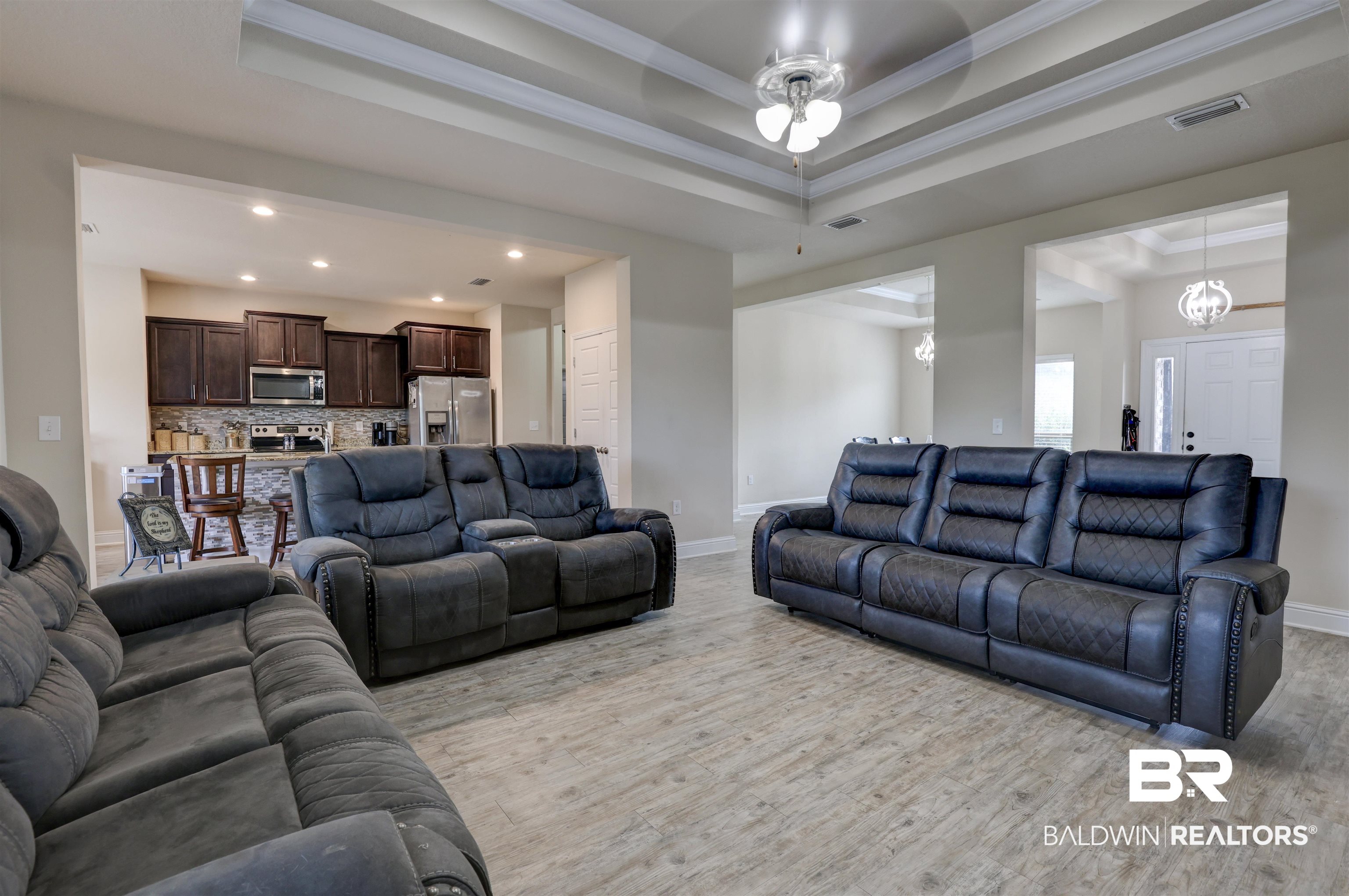 21902 Yosemite Boulevard Fairhope, AL 36532 - Photo 6 of 32 Living room with light hardwood / wood-style flooring, a notable chandelier, a tray ceiling, and ornamental molding