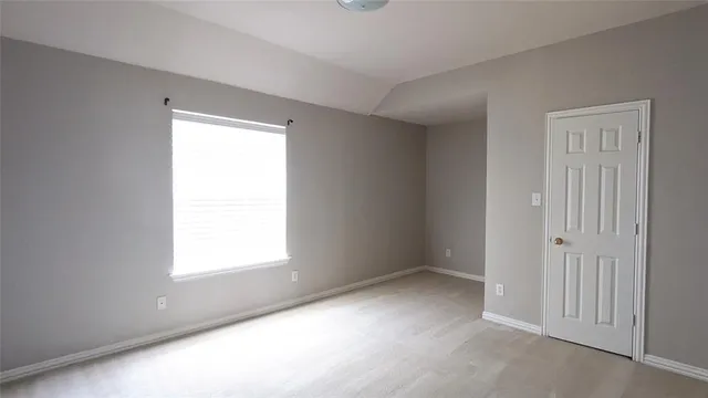 an empty room with fireplace cabinet and windows