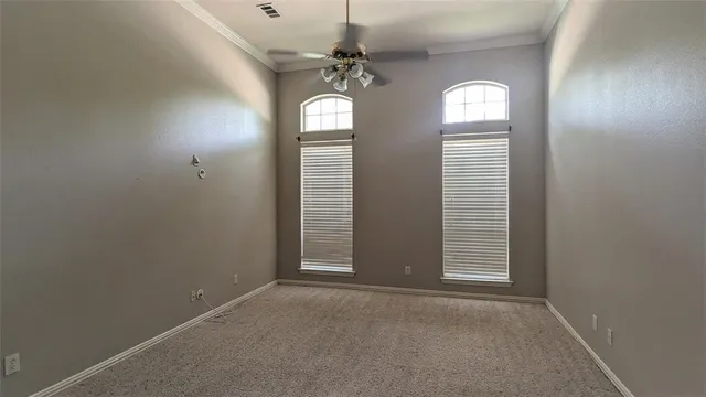 an empty room with windows and chandelier fan