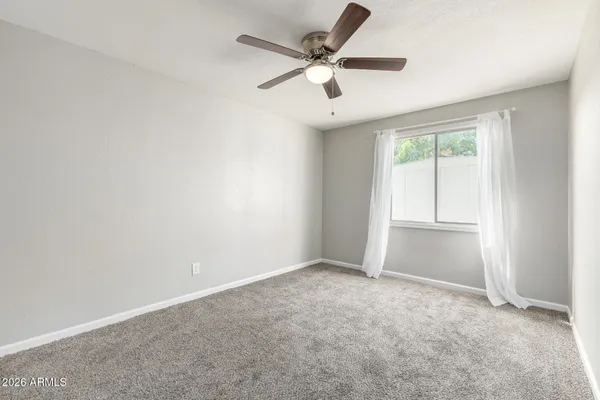 an empty room with a ceiling fan and a window