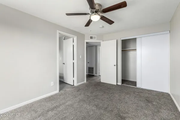 an empty room with closet and a ceiling fan