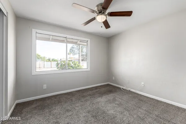 an empty room with a window and a fan