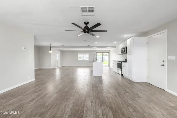 a view of a big room with wooden floor a ceiling fan and windows