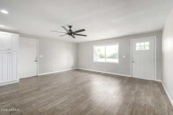an empty room with wooden floor window and ceiling fan