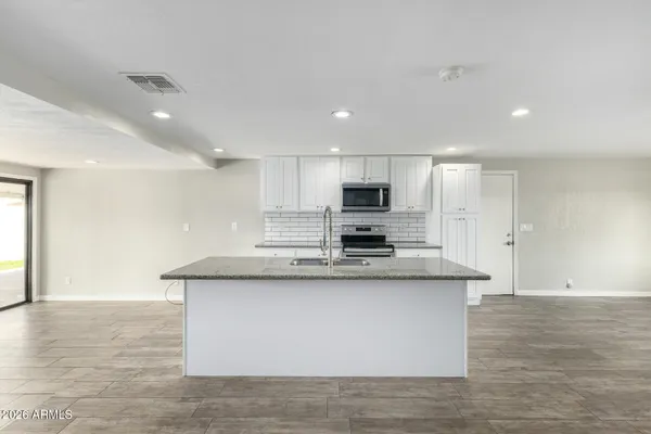a view of kitchen with stainless steel appliances granite countertop cabinets and wooden floor