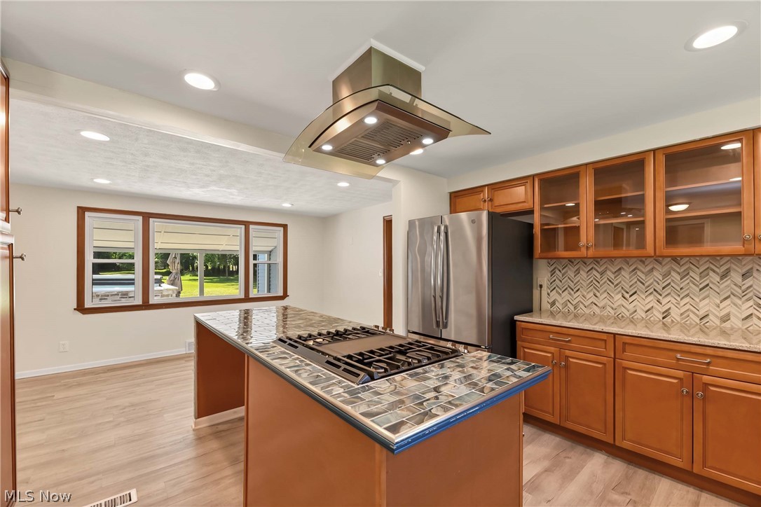 29514 Ridge Road Wickliffe, OH 44092 - Photo 21 of 49 Kitchen with light wood-type flooring, a kitchen island, island range hood, appliances with stainless steel finishes, and tasteful backsplash