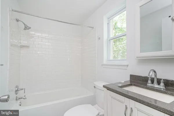 a bathroom with a granite countertop sink a toilet and shower