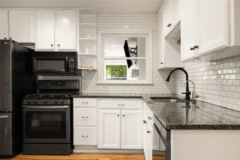 a kitchen with granite countertop a stove a sink and a microwave
