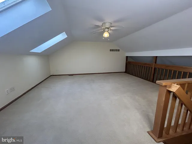 a view of an empty room with chandelier fan