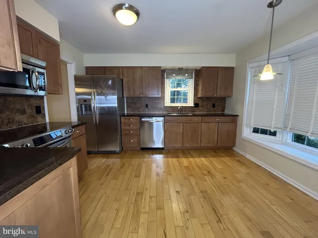 a large kitchen with stainless steel appliances granite countertop a stove a sink dishwasher and a refrigerator