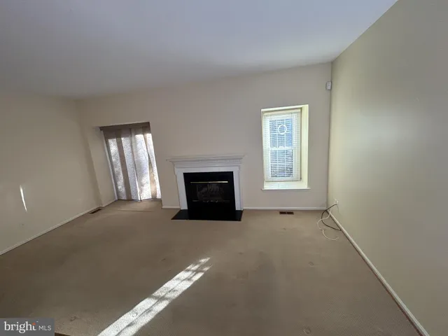 a view of an empty room with a fireplace and a window