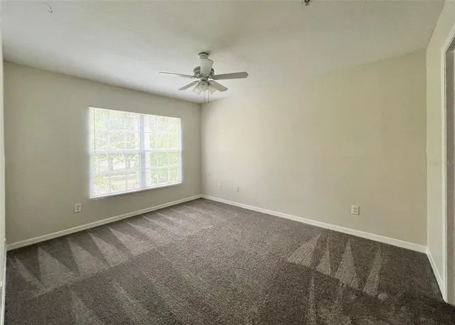 an empty room with windows and fan