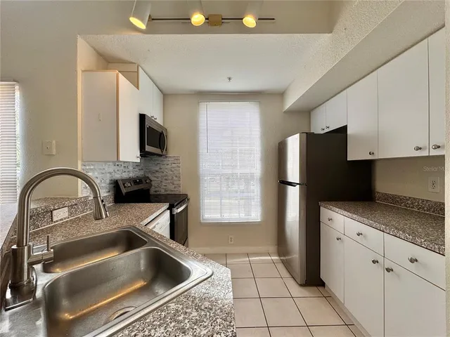 a kitchen with a refrigerator sink and white cabinets