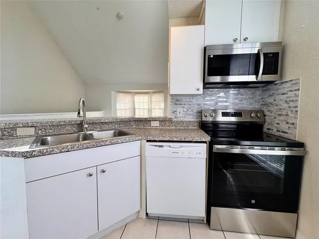 a kitchen with stainless steel appliances granite countertop a sink a stove a microwave and wooden cabinets