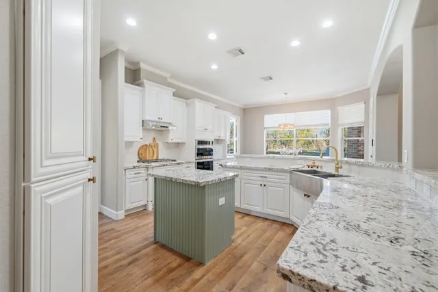 a kitchen with granite countertop a sink and white cabinets