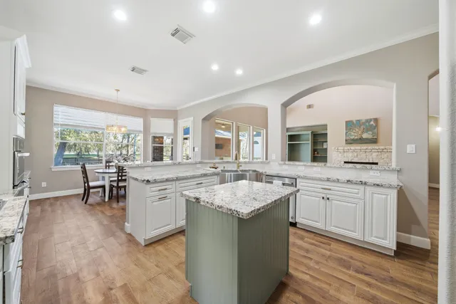 a kitchen with stainless steel appliances a dining table chairs stove refrigerator and cabinets