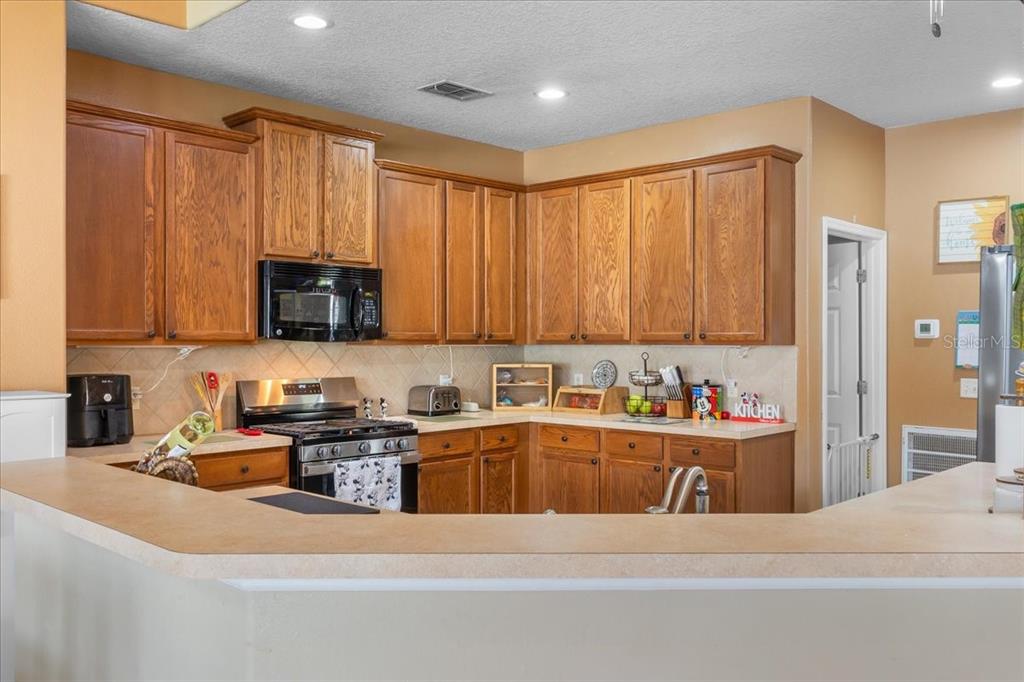 817 James Way Lake Alfred, FL 33850 - Photo 28 of 69 a kitchen with stainless steel appliances a sink a stove a refrigerator cabinets and a counter top space
