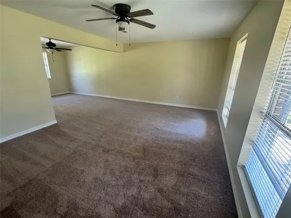 an empty room with a window and a fan