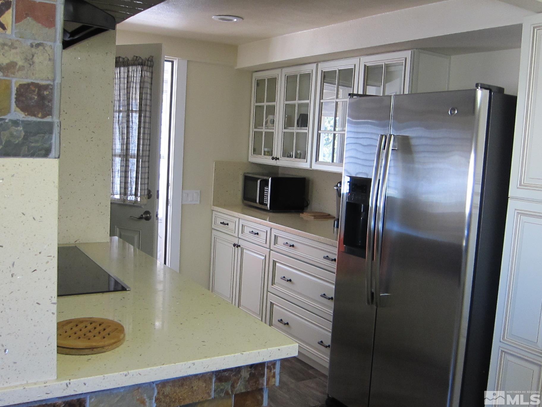 16770 Mt Rose Highway, Unit A & B Reno, NV 89511 - Photo 31 of 40 a kitchen with stainless steel appliances granite countertop a refrigerator a stove and white cabinets with wooden floor
