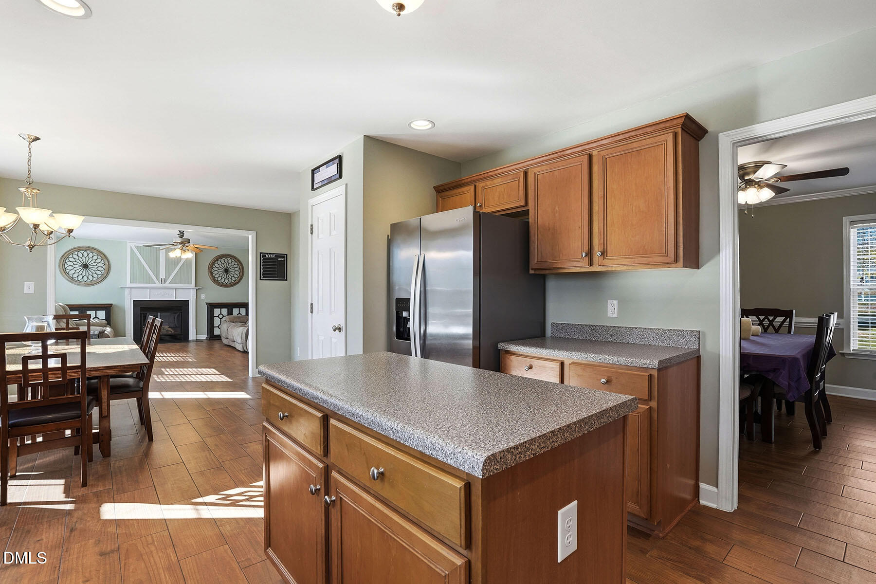 90 Spring Leaf Lane Wendell, NC 27591 - Photo 10 of 37 a kitchen with kitchen island a stove a refrigerator a dining table and chairs with wooden floor