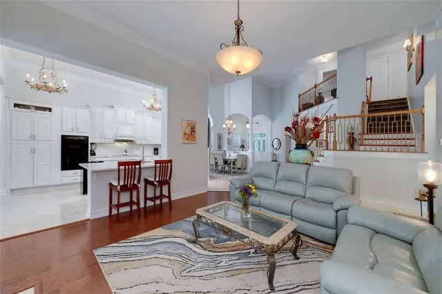 a living room with furniture kitchen view and a chandelier