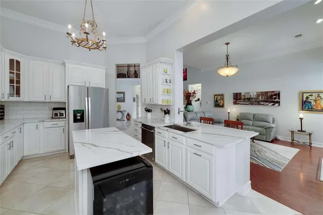 a kitchen that has a lot of white cabinets and stainless steel appliances