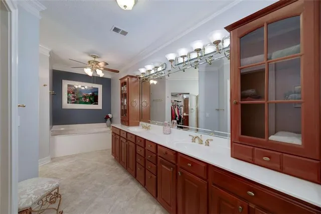 a spacious bathroom with a double vanity sink a large mirror and a bathtub