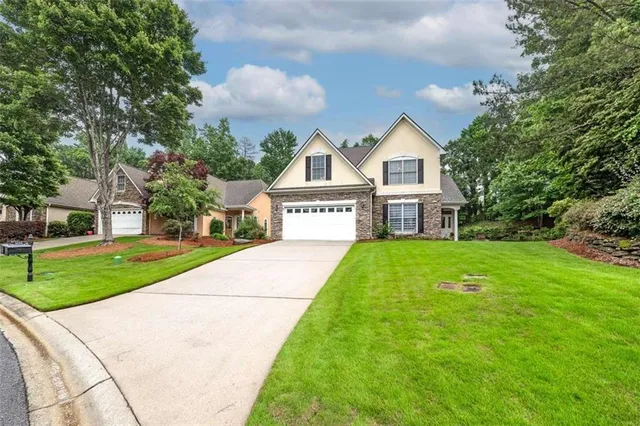 a view of a house with a yard and large trees