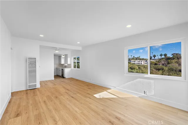 a view of an empty room with a window and wooden floor