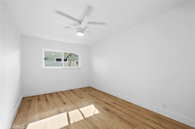 an empty room with wooden floor ceiling fan and windows