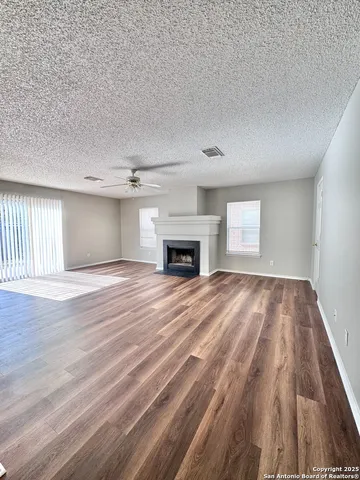 an empty room with wooden floor fireplace and windows