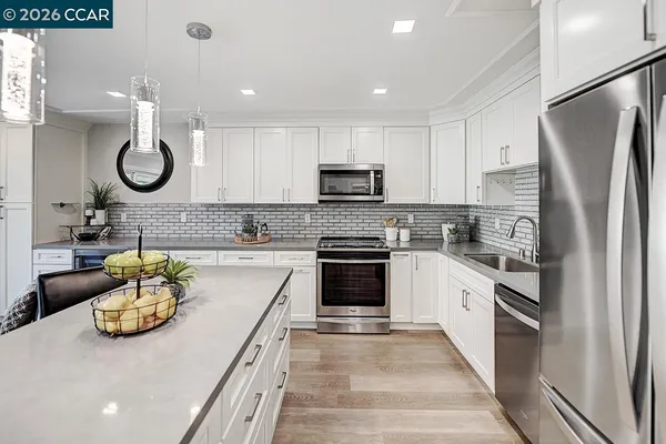 a kitchen with stainless steel appliances granite countertop a sink a stove top oven a refrigerator a stove and white cabinets