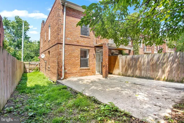 a view of a backyard with wooden fence and large trees