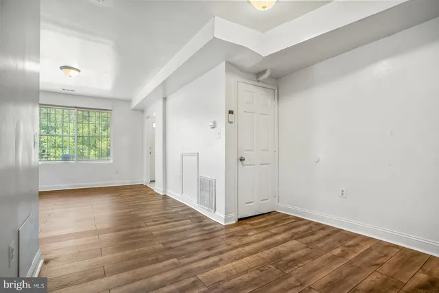 an empty room with wooden floor closet and windows