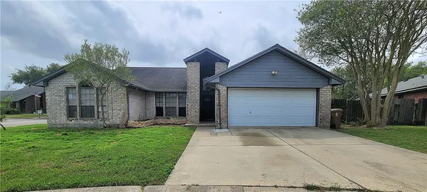 a front view of house with yard and trees in the background