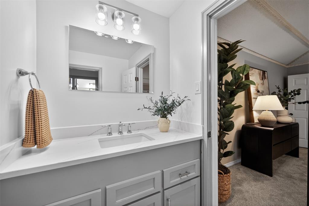 9660 Timberleaf Drive Dallas, TX 75243 - Photo 33 of 40 Vanity featuring a rectangular undermount sink, a stone-finish countertop, and chrome fixtures