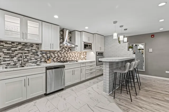 a kitchen with stainless steel appliances kitchen island granite countertop a stove a sink and a microwave