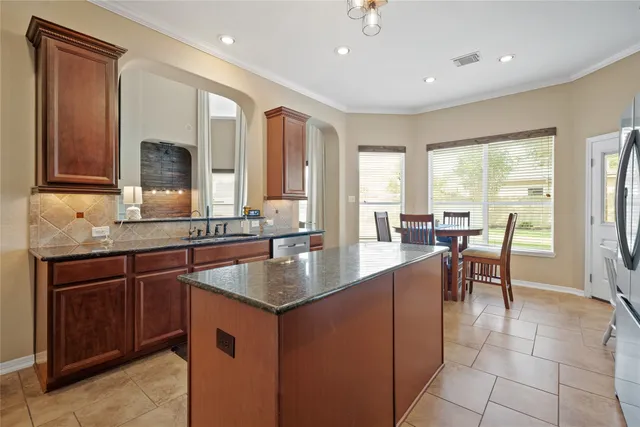 a kitchen with kitchen island granite countertop a sink a counter top space and stainless steel appliances