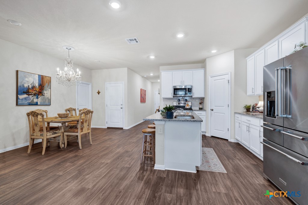 1444 Harwell Loop Kyle, TX 78640 - Photo 6 of 37 a kitchen with kitchen island wooden floors appliances and dining table