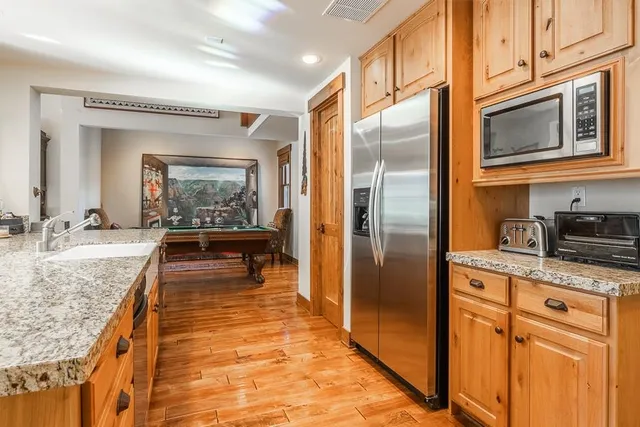 a kitchen with stainless steel appliances granite countertop a refrigerator a stove and a sink with wooden floor