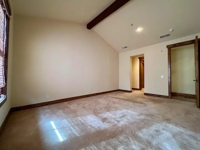 an empty room with wooden floor and windows with curtains