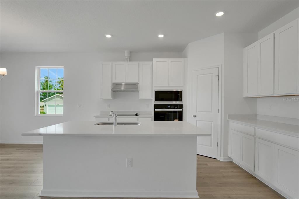 2857 Doolittle Street Tavares, FL 32778 - Photo 23 of 31 a kitchen with kitchen island white cabinets and stainless steel appliances