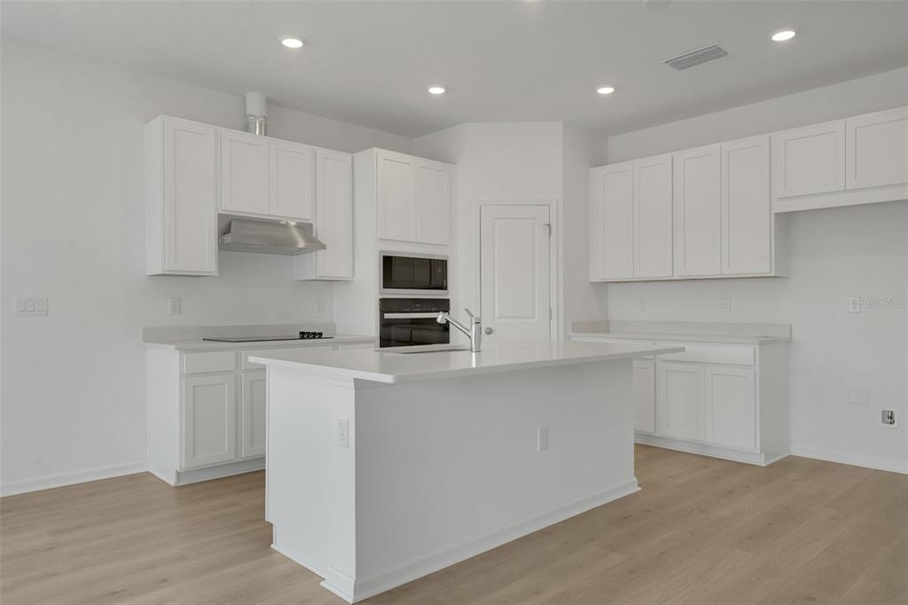 2857 Doolittle Street Tavares, FL 32778 - Photo 4 of 31 a kitchen with stainless steel appliances a stove top oven a sink and white cabinets