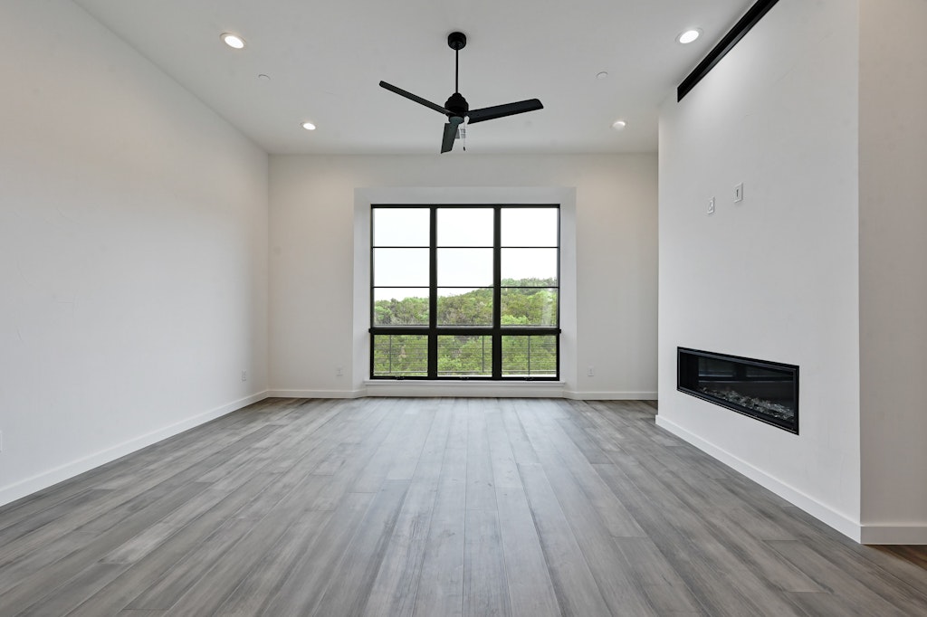 6805 Adeline Way, Unit 17 Austin, TX 78746 - Photo 13 of 38 Unfurnished living room featuring ceiling fan, recessed lighting, light wood-style flooring, and a glass covered fireplace
