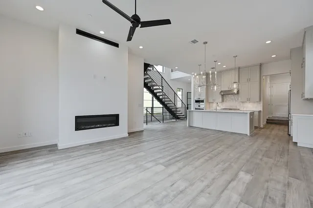 a view of an empty room with wooden floor kitchen view and a living room