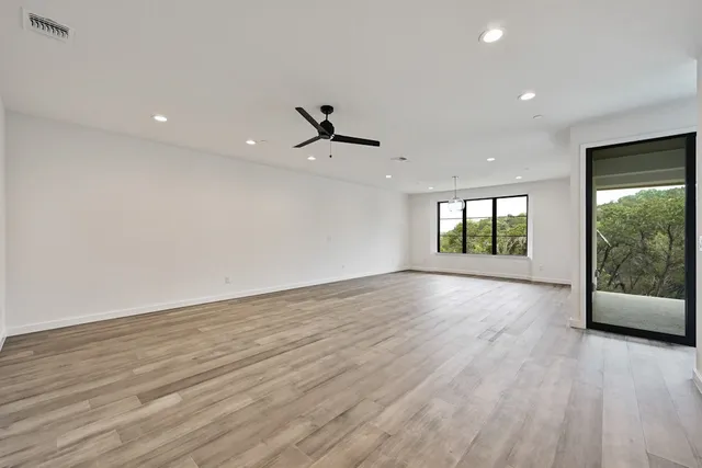 a view of an empty room with a window and wooden floor