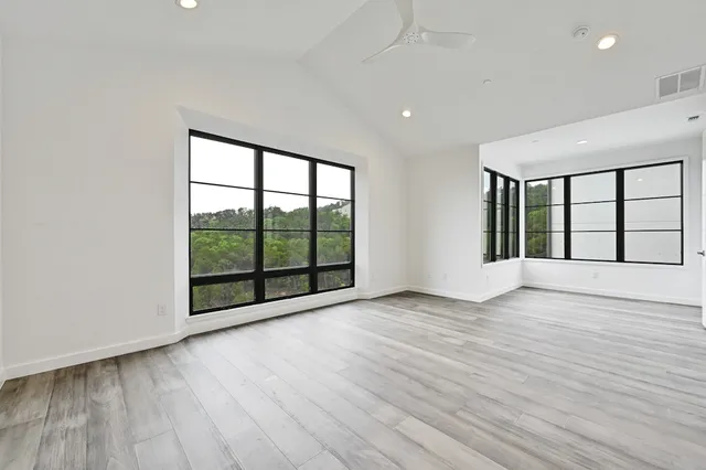 a view of an empty room with wooden floor and a window