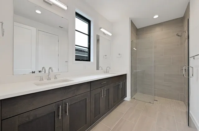 a bathroom with a double vanity sink mirror and shower