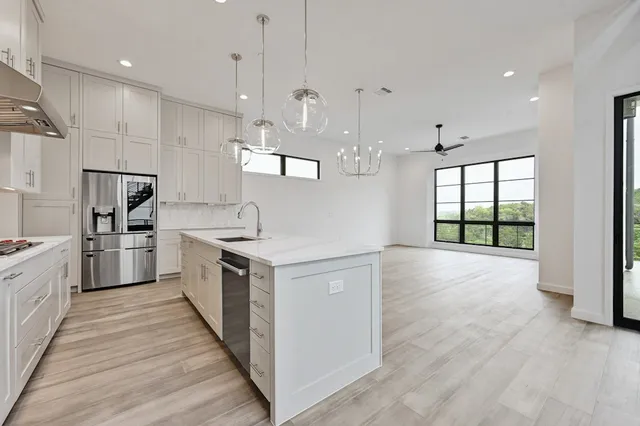 a large kitchen with kitchen island a large counter space a sink stainless steel appliances and cabinets
